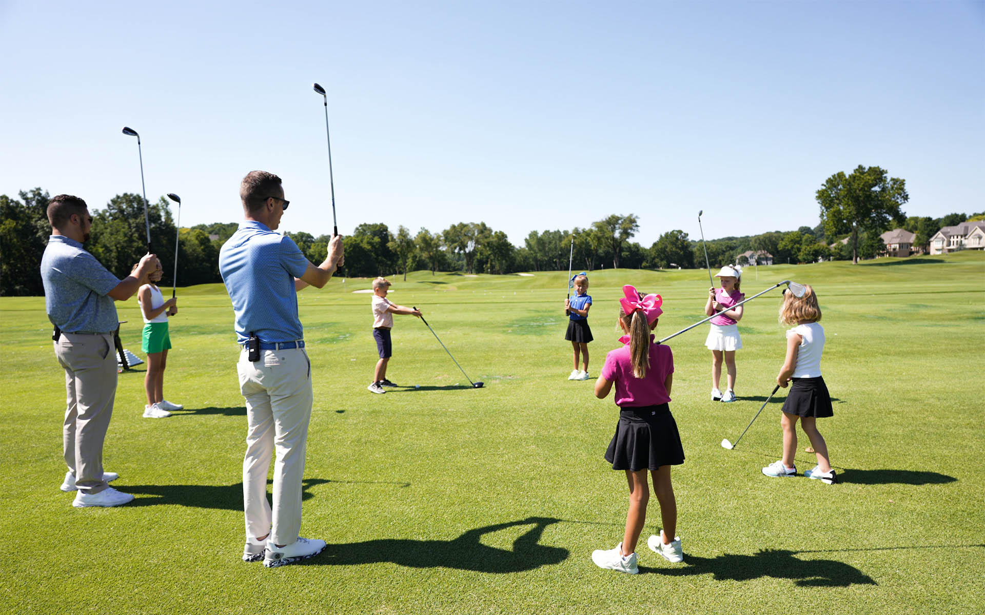 Invited Crush It! Junior Golf Clinic in action: Expert coaches guiding young children in learning the golf grip on an Invited Club driving range